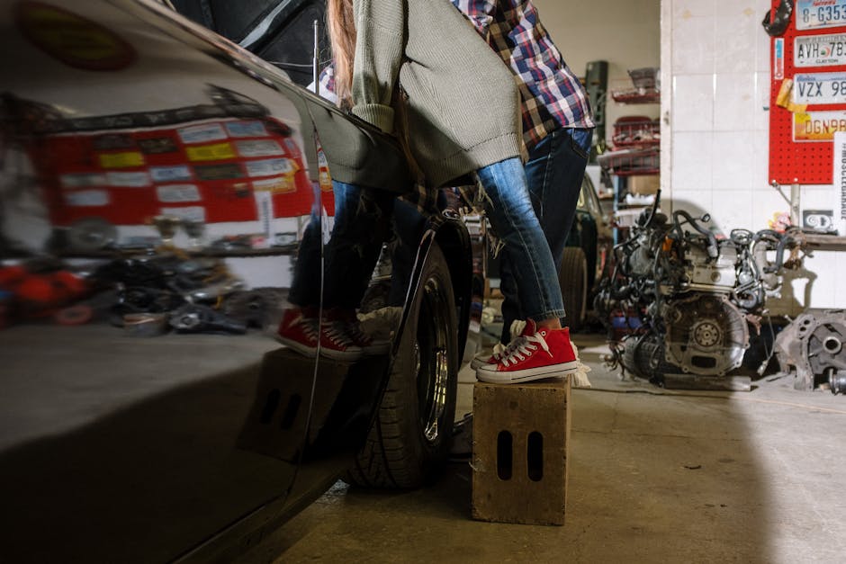 A father and daughter bonding while working on a car in a repair shop, showcasing teamwork and family.