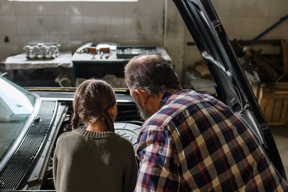Father and daughter working together under the car hood in a cozy garage.